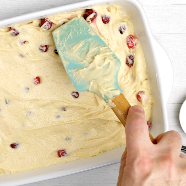 Cranberry cake batter being spread evenly in pan.