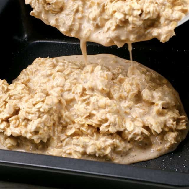 Baked blueberry oatmeal batter being poured into a greased pan.