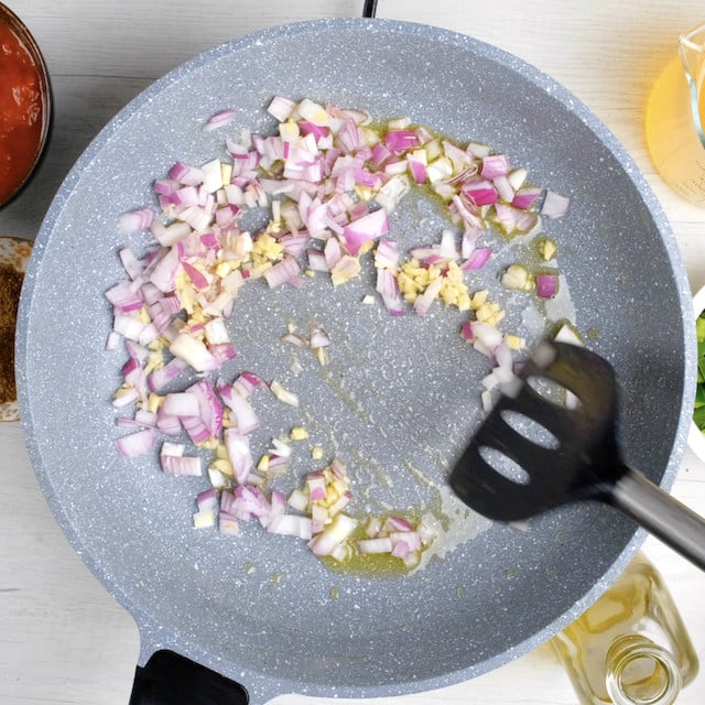 Onion and garlic being sautéed in a pan.