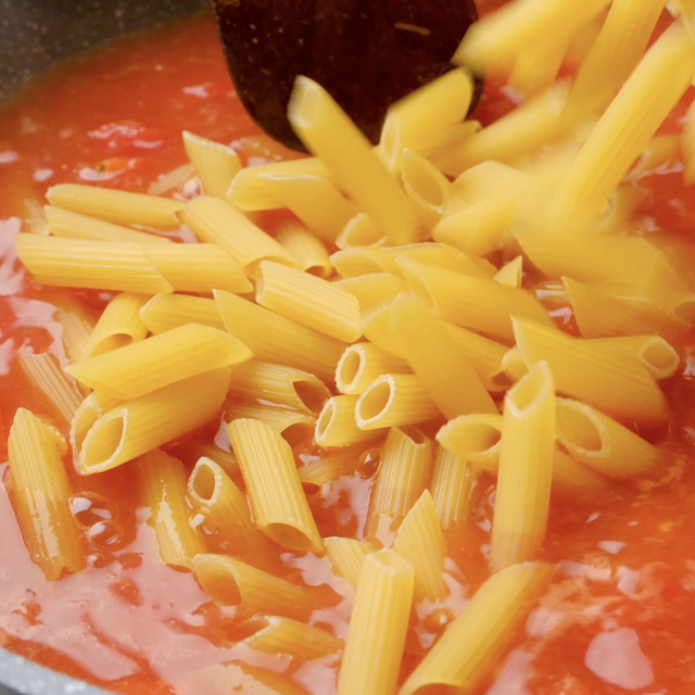 Uncooked pasta being added to a pot to make chicken fajita pasta.