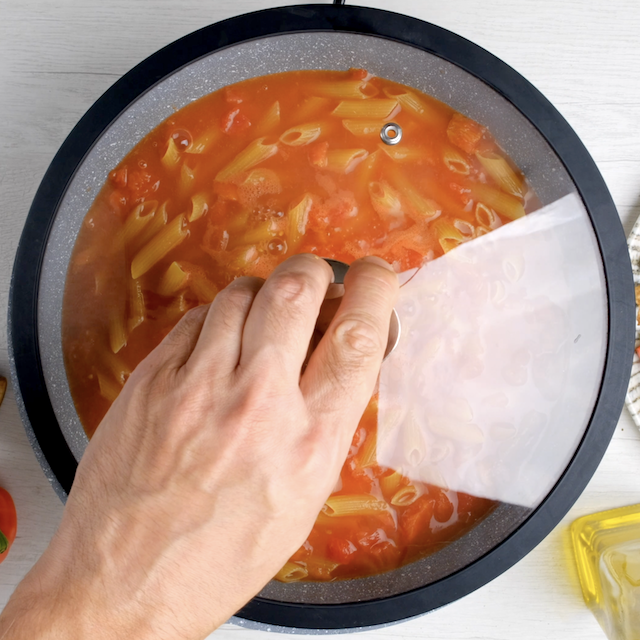 A lid being put on top of a pot with chicken fajita pasta.