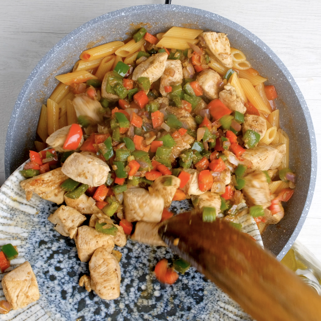 Cooked chicken and veggies being returned to pot with cooked pasta to make chicken fajita pasta.