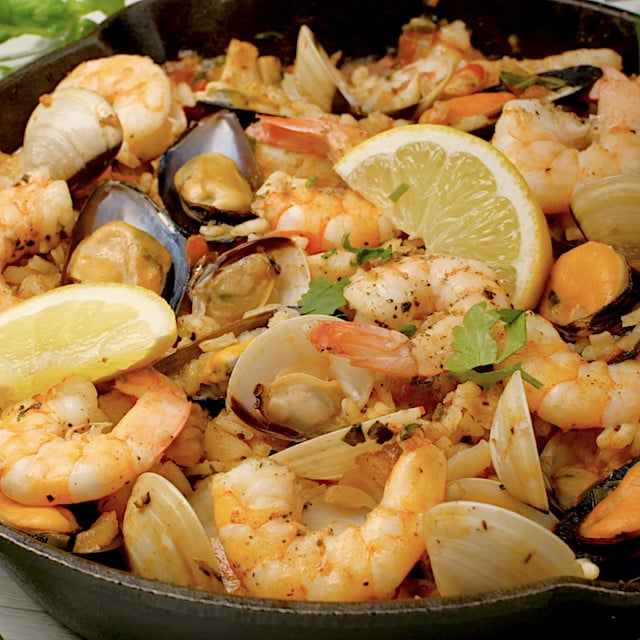 Lemon wedges being served with freshly made seafood paella.