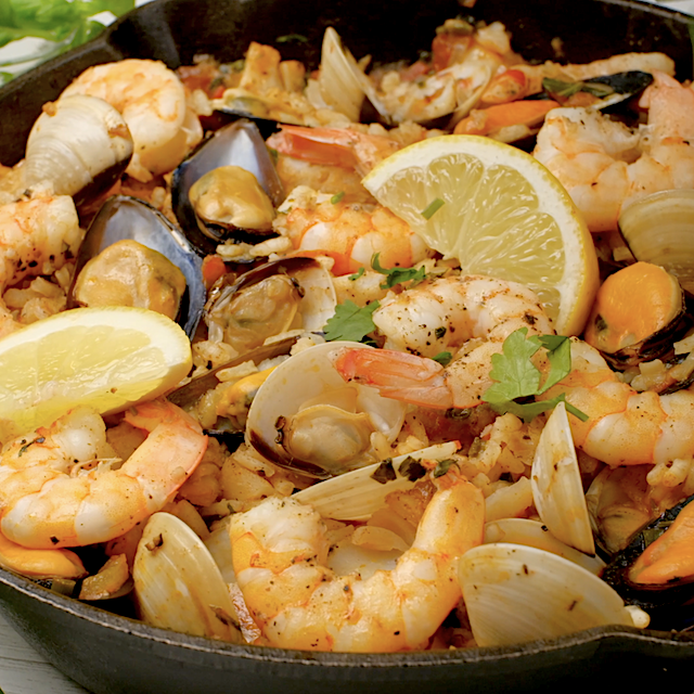 Lemon wedges being served with freshly made seafood paella.