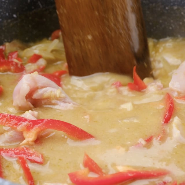 Bell peppers being stirred into Thai chicken curry.