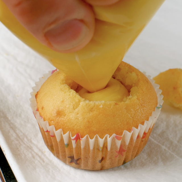 Cupcakes being filled with pastry cream in the center to make boston cream cupcakes.