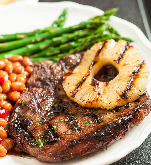 grilled pork chops with pineapple rings on a plate