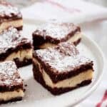 Close up of cheesecake brownie on a white serving plate.