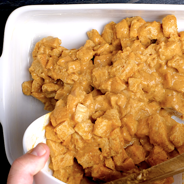 Pumpkin bread pudding mixture being transferred to a lightly greased baking dish.