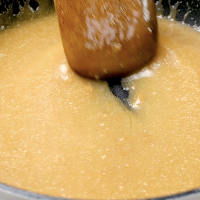 Caramel sauce being stirred in a pan for pumpkin bread pudding.