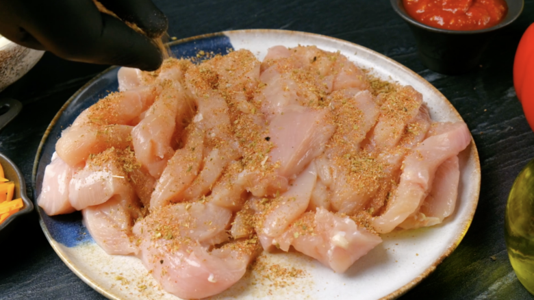 Chicken strips tossed with fajita seasoning to make sheet pan chicken fajitas.