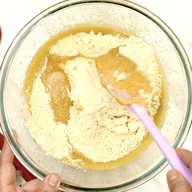 Dry ingredients being folded into wet ingredients to make pumpkin cornbread.