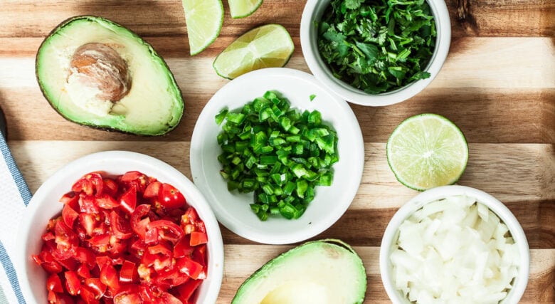 Guacamole ingredients including avocado, tomatoes, onion, lime, cilantro.