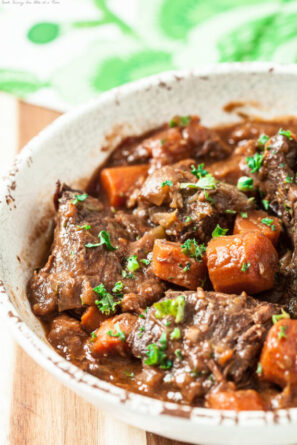 side image of a bowl of slow cooker pot roast topped with fresh herbs