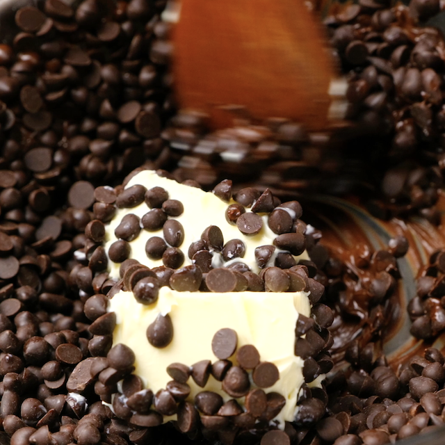 Chocolate chips being stirred with butter in a pot.