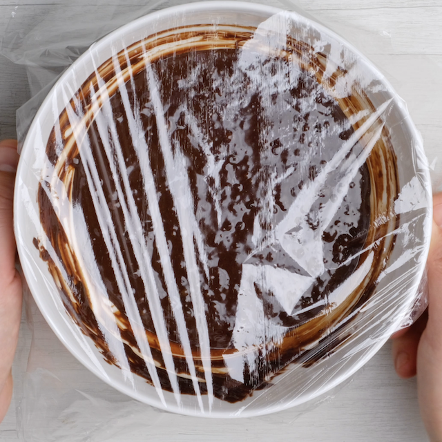 Plastic wrap covering a bowl with brownie cookie batter.