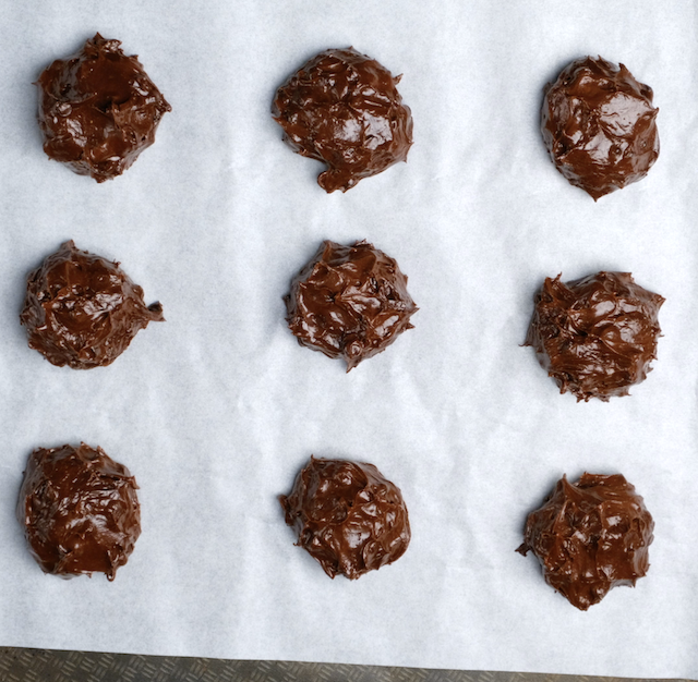 Chewy brownie cookie balls on a parchment lined sheet for baking.