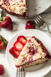 strawberry crumb caked, sliced with fresh berries on white plate