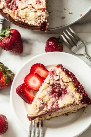 strawberry crumb caked, sliced with fresh berries on white plate