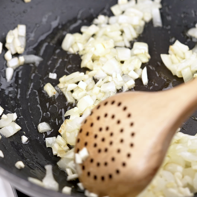 Onions and garlic being sauteed to make thai basil chicken.