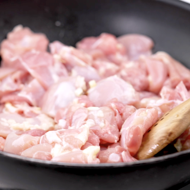 Chicken being cooked in a pan to make thai basil chicken.