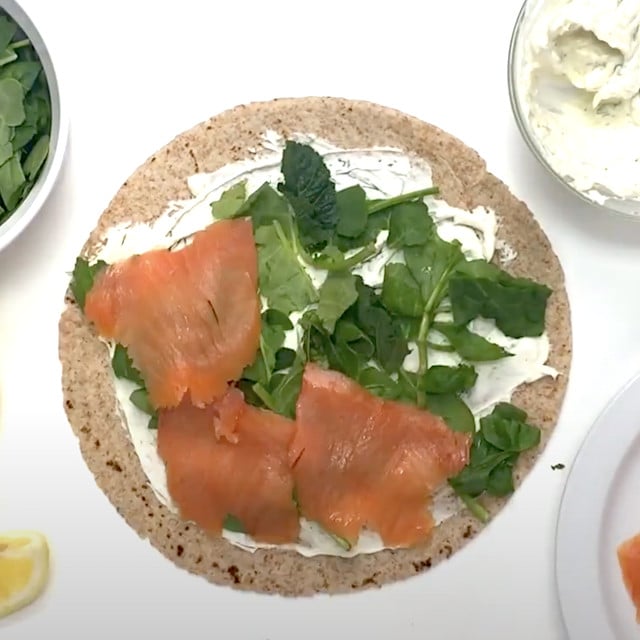 Spinach leaves and smoked salmon layered on top of creamy lemon dill spread to make smoked salmon pinwheels at home.