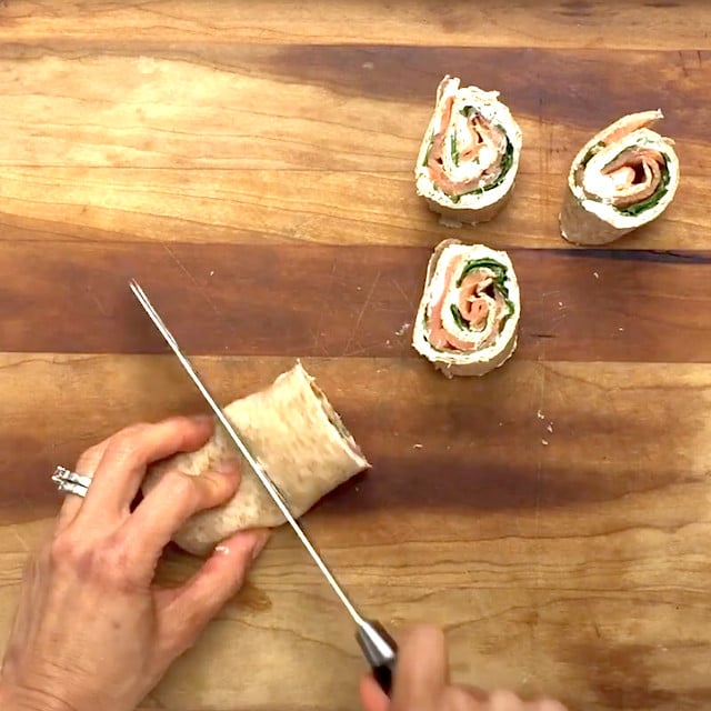 Pinwheels being sliced to make smoked salmon pinwheels at home.