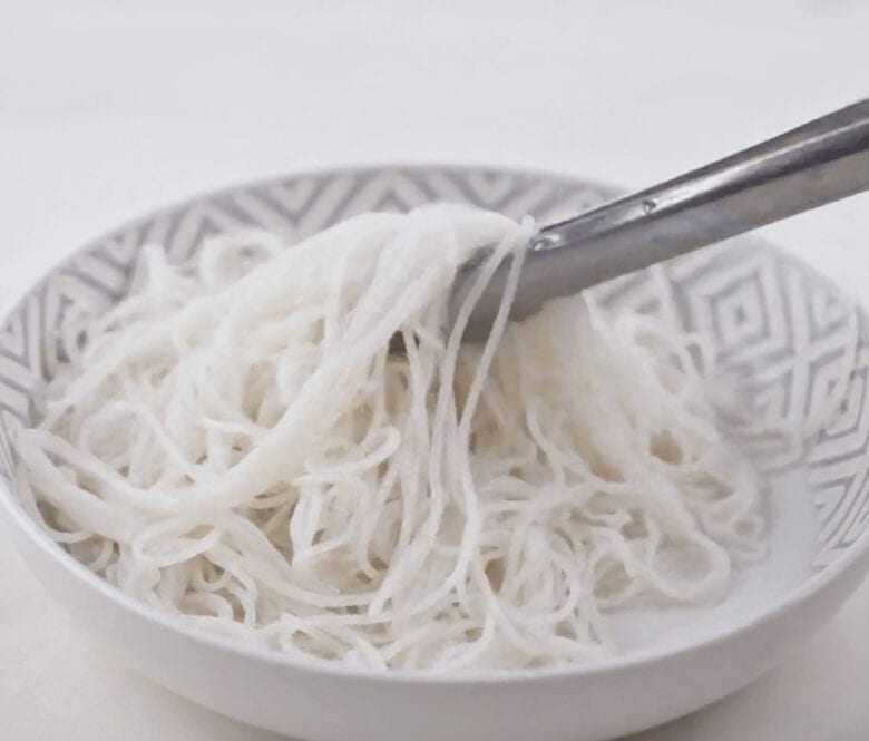 Cooking the rice noodles and putting them in a serving bowl.