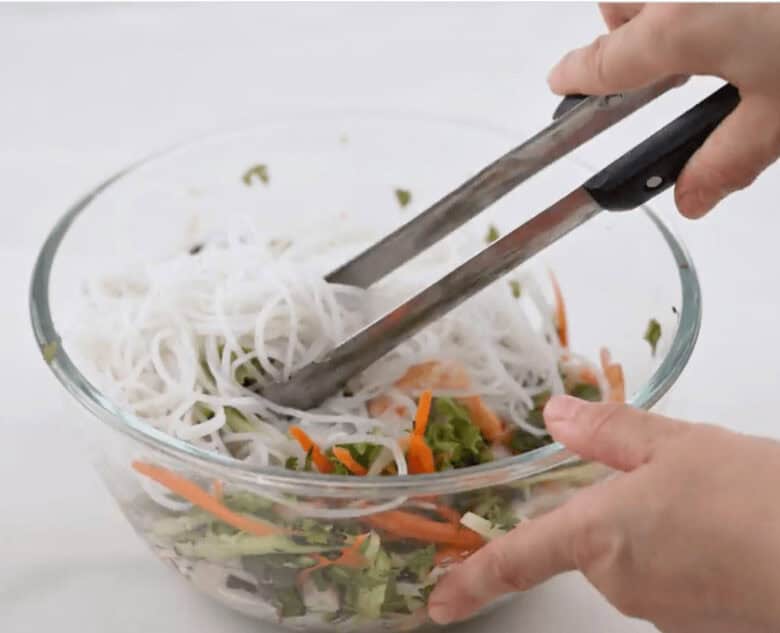 Adding the cooked rice noodles to the other ingredients for the Spring Roll Bowl.