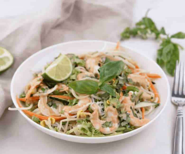 Spring roll bowl in white bowl garnished with slice of lime.