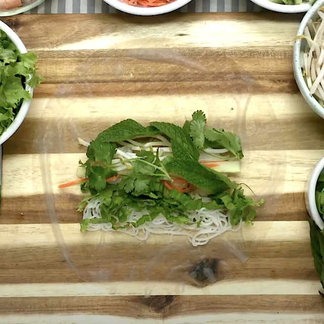 Vietnamese spring roll fillings on a soaked rice paper wrapper on a chopping board.