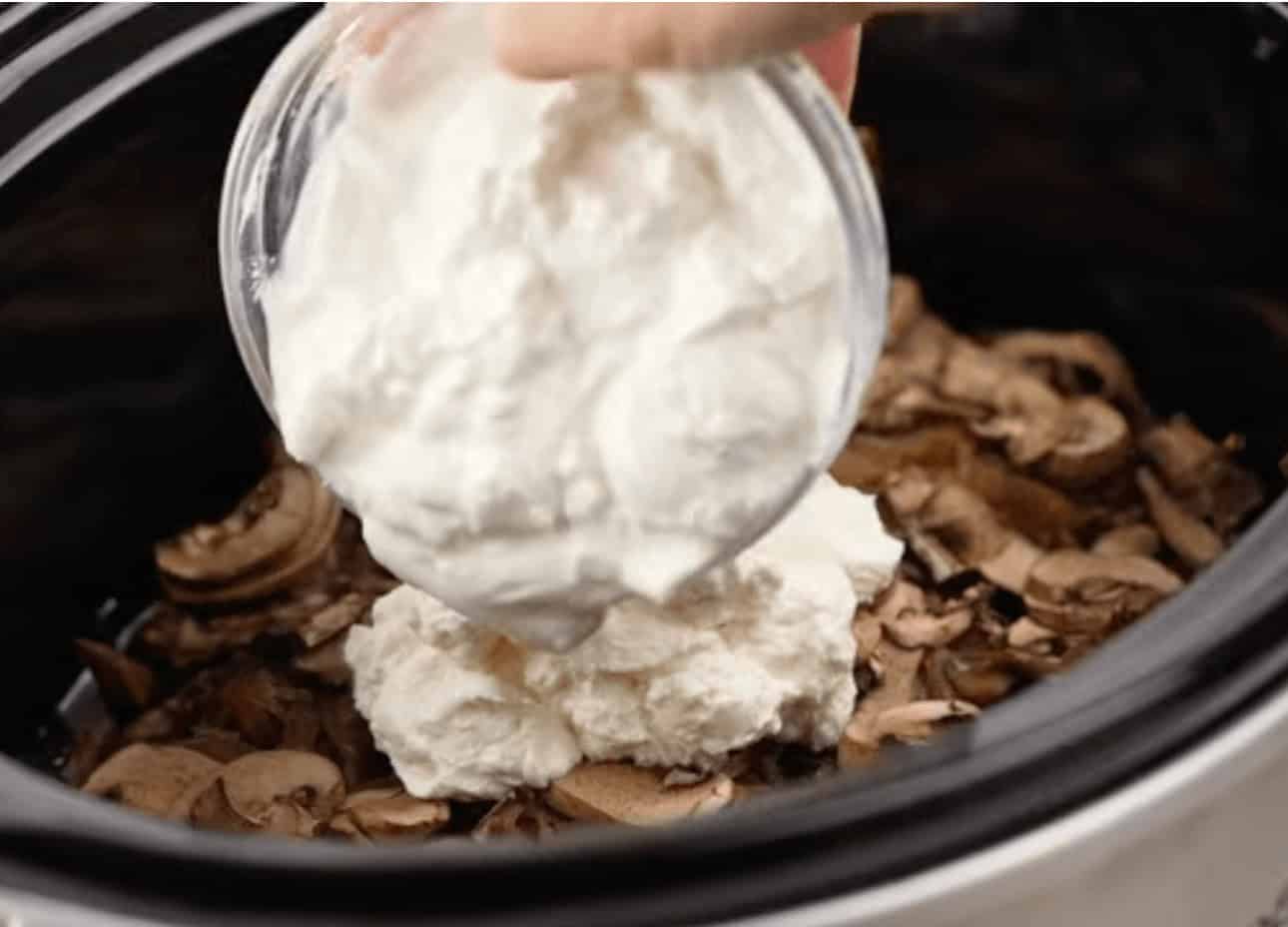 Adding the cream cheese mixture into the slow cooker.