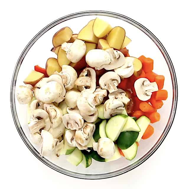 Chopped vegetables and potatoes in a glass bowl to make easy roasted vegetables.