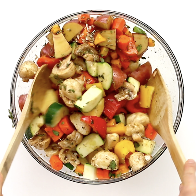 Veggies being tossed to coat them in seasoning, herbs, and balsamic to make easy roasted vegetables.