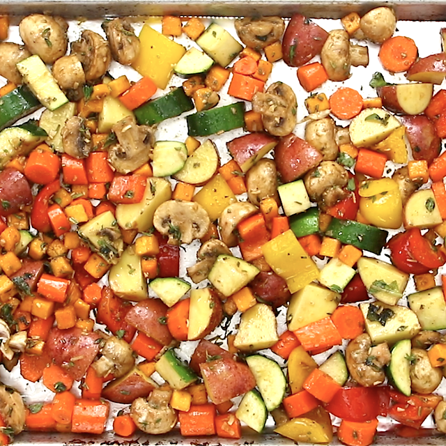 Chopped and seasoned vegetables spread on a baking sheet, ready to be roasted to make easy roasted vegetables.
