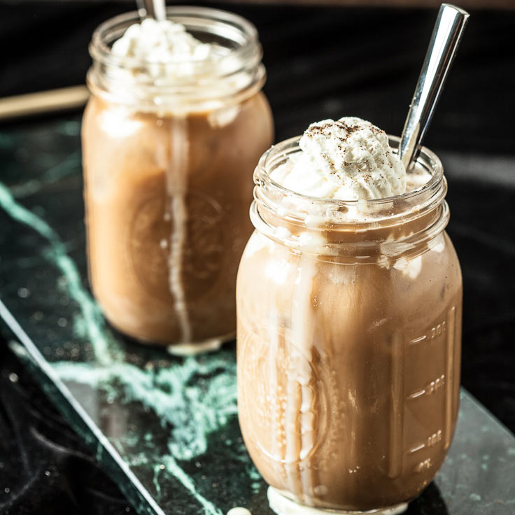 thai iced coffee with whipped cream in glass mugs