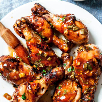 grilled chicken legs on a white plate with marinade