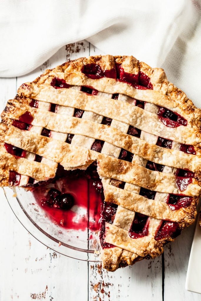 homemade cherry pie with lattice crust and a piece of pie cut out