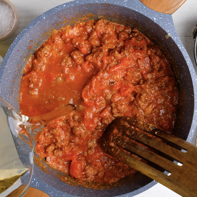 Broth being poured in a pot to make easy lasagna soup.
