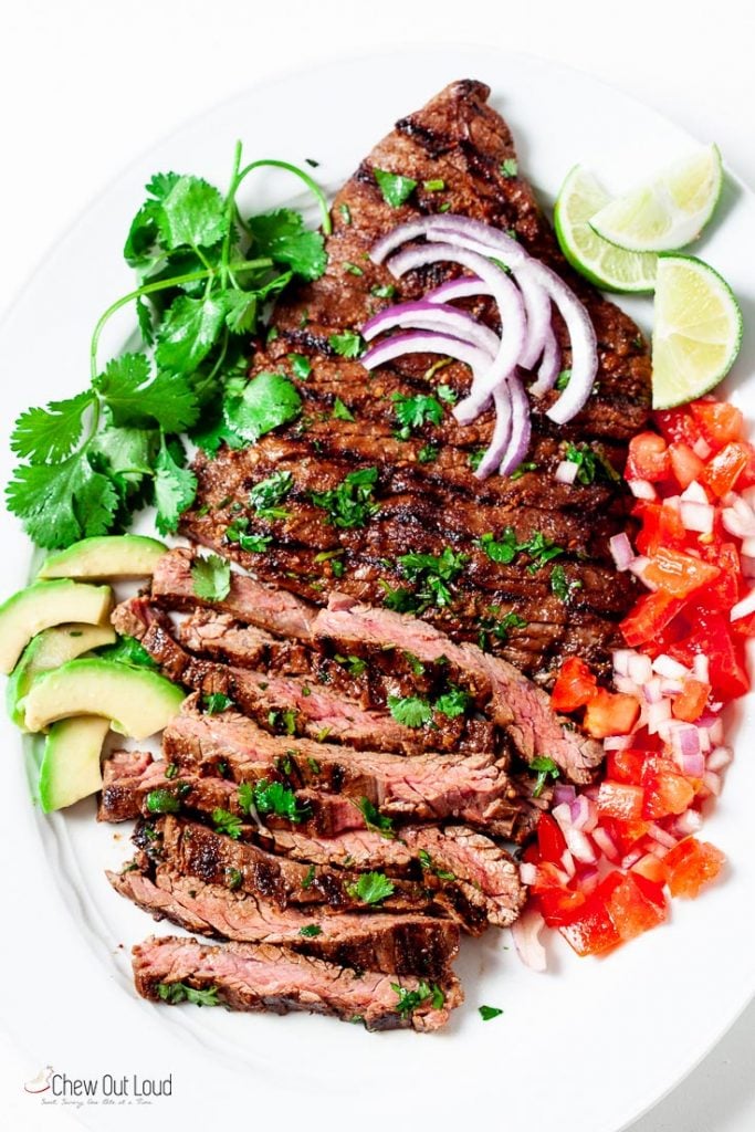 carne asada sliced on a plate with avocado and salsa