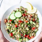 A plate of Tabbouleh with sliced of lemon and cucumber