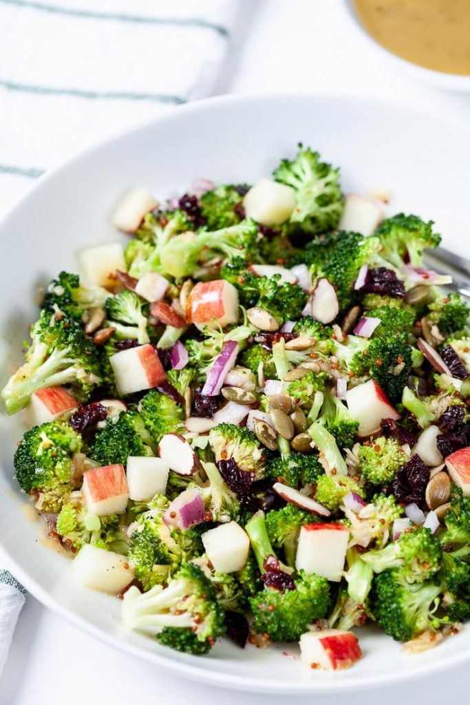 broccoli apple salad in a white bowl with honey mustard dressing