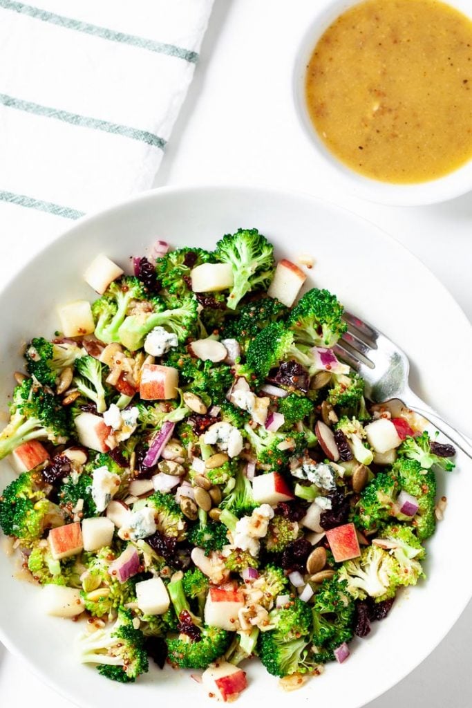 broccoli apple salad in a white bowl with honey mustard dressing