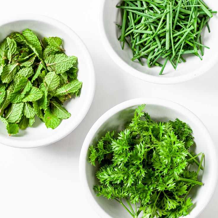 A bowl of chopped parsley, mint, and green onion