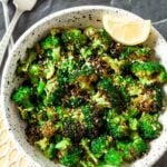 Air Fryer Broccoli florets in a bowl garnished with lemon slice.