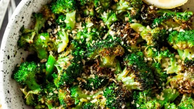 Air Fryer Broccoli in a bowl with fork and lemon slices for garnish.
