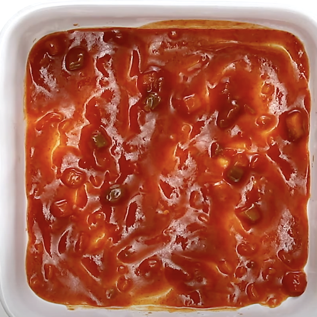 Enchilada sauce mixed with fire-roasted tomatoes in a baking dish to make Mexican Breakfast Casserole.