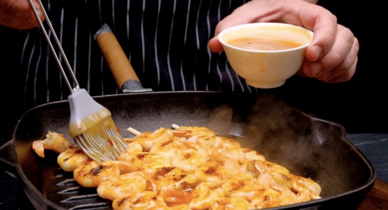 shrimp skewers being brushed with butter