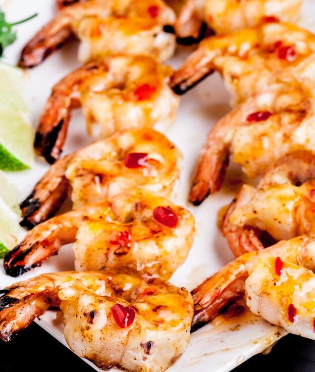 Grilled Shrimp kabobs on a white plate with thai sauce