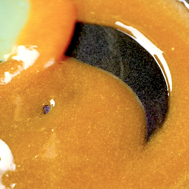 Honey glaze sauce being heated in a saucepan until thickened.
